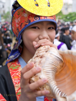 A young girl plays a traditional conch shell horn at the Eisa dance along Kokusai Street