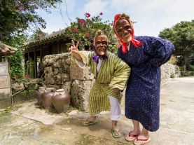 Traditional Okinawan dancers wearing masks of smiling elderly people at Ryukyu Mura, Okinawa, Japan